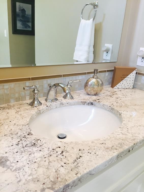 Example of a mid-sized transitional master white tile and porcelain tile porcelain tile and brown floor corner shower design with an undermount sink, recessed-panel cabinets, white cabinets, granite countertops, a one-piece toilet, beige walls, a hinged shower door and multicolored countertops