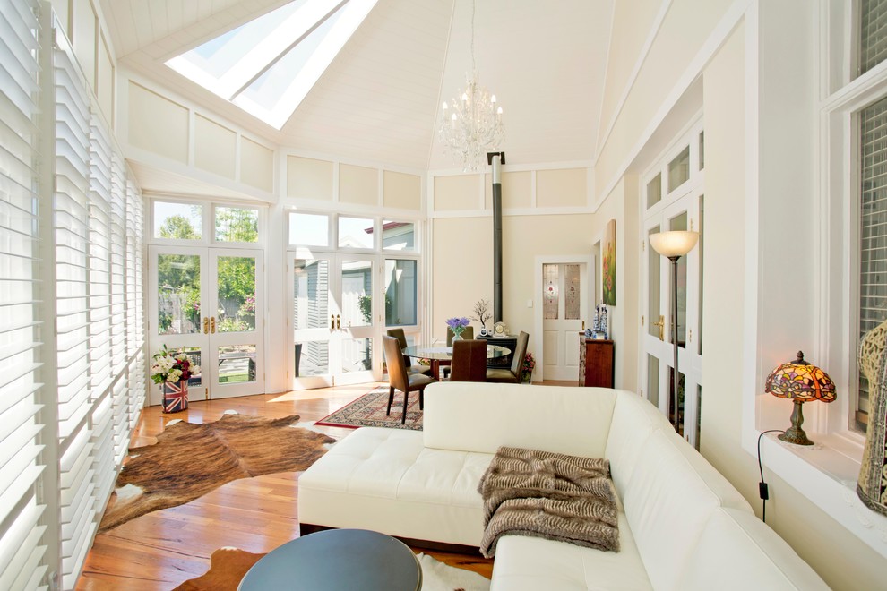 Large traditional open concept living room in Sydney with white walls, medium hardwood floors and a standard fireplace.