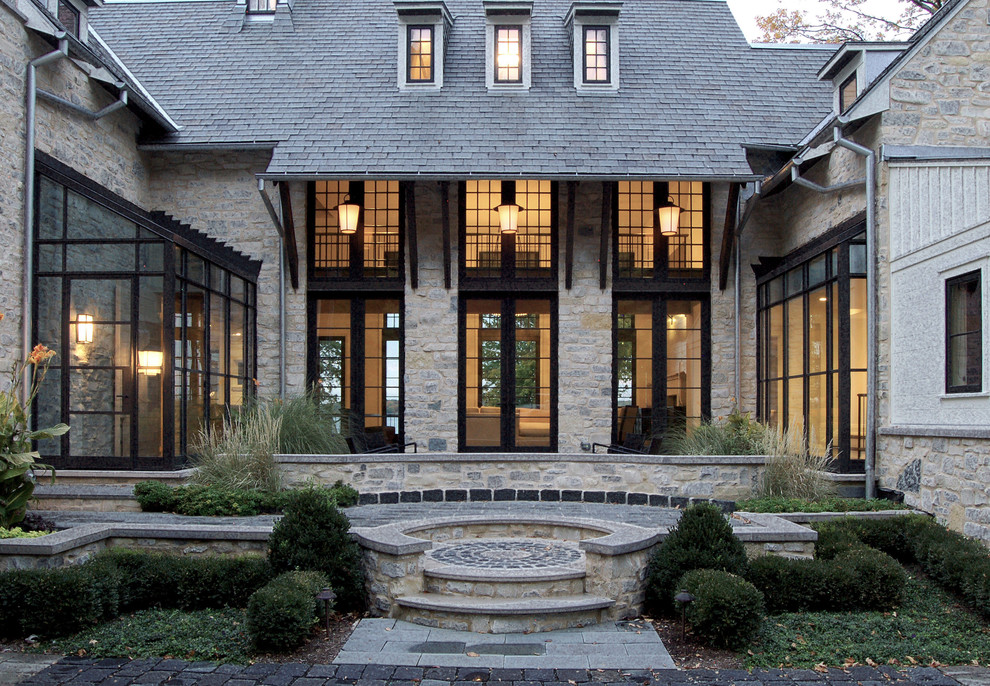 This is an example of a traditional three-storey grey exterior in Milwaukee with stone veneer and a hip roof.