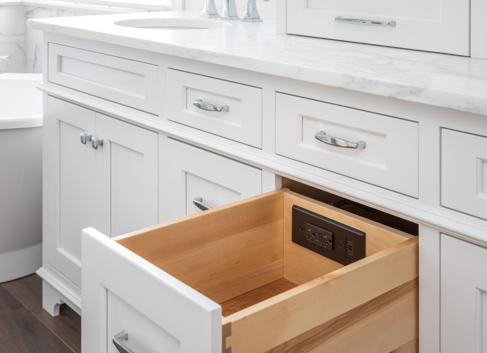 Inspiration for a mid-sized transitional master white tile and marble tile dark wood floor and brown floor freestanding bathtub remodel in Raleigh with recessed-panel cabinets, white cabinets, beige walls, an undermount sink, marble countertops, a hinged shower door and white countertops