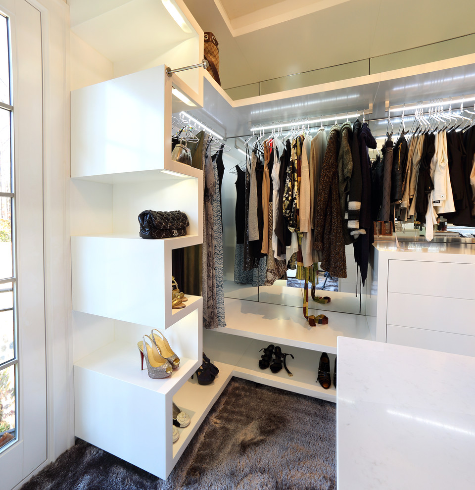 This is an example of a large contemporary women's walk-in wardrobe in Baltimore with flat-panel cabinets, white cabinets and carpet.