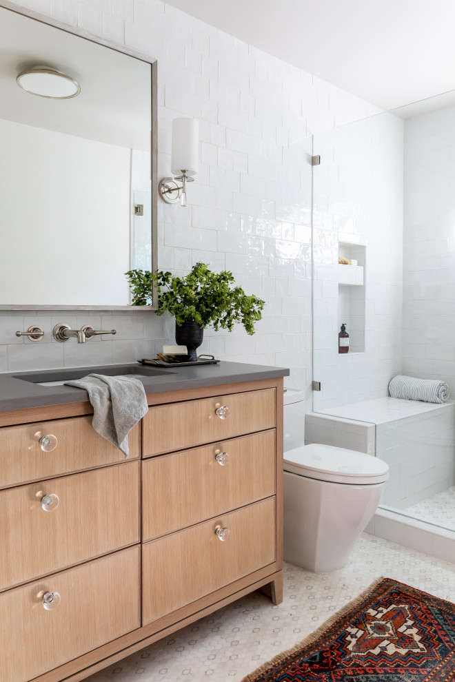Design ideas for a classic bathroom with flat-panel cabinets, light wood cabinets, an alcove shower, white tiles, metro tiles, a submerged sink, white floors, grey worktops, a wall niche, a shower bench, a single sink and a built in vanity unit.