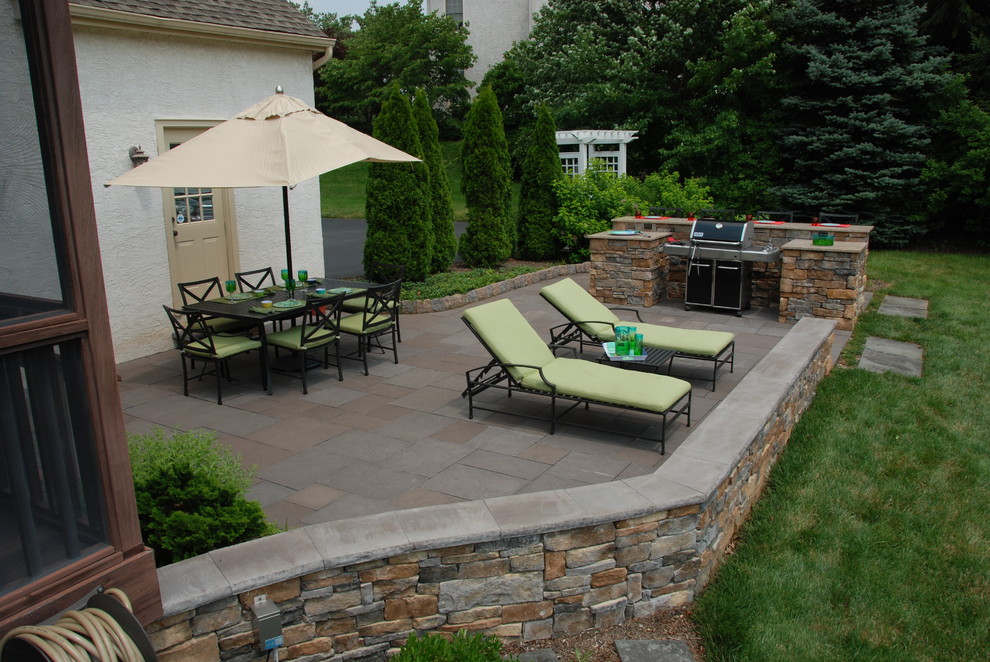 Photo of a small traditional backyard patio in Philadelphia with natural stone pavers and an outdoor kitchen.