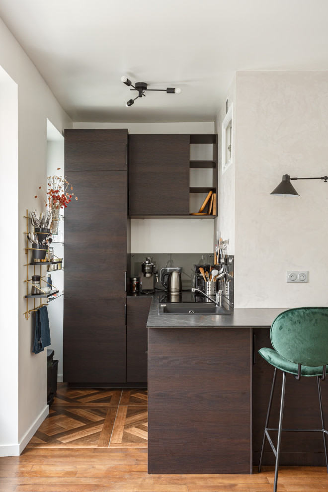 Inspiration pour une petite cuisine ouverte design en L et bois foncé avec un placard à porte affleurante, un plan de travail en granite, un sol marron et plan de travail noir.