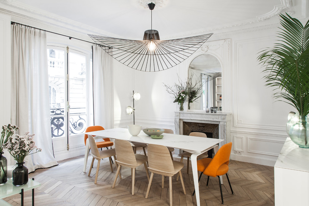 Mid-sized contemporary open plan dining in Paris with white walls, a standard fireplace, a stone fireplace surround, medium hardwood floors and brown floor.