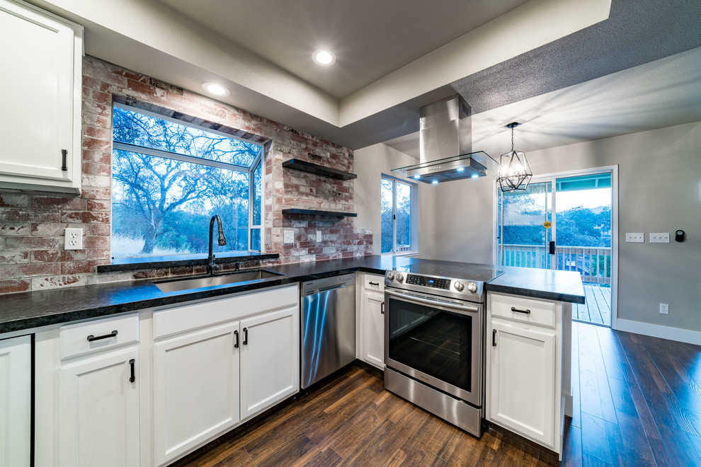 Example of a mid-sized transitional u-shaped dark wood floor and brown floor enclosed kitchen design with a triple-bowl sink, recessed-panel cabinets, white cabinets, granite countertops, red backsplash, brick backsplash, stainless steel appliances and a peninsula