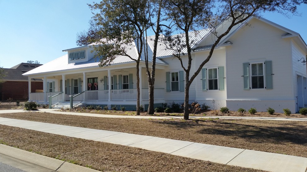 Mid-sized country one-storey stucco white house exterior in Other with a hip roof and a metal roof.