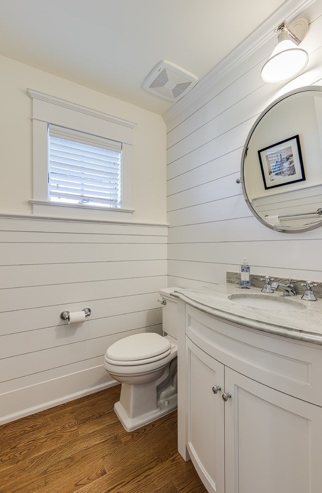 This is an example of a small beach style 3/4 bathroom in Philadelphia with flat-panel cabinets, white cabinets, a one-piece toilet, white walls, medium hardwood floors, a drop-in sink, marble benchtops and brown floor.