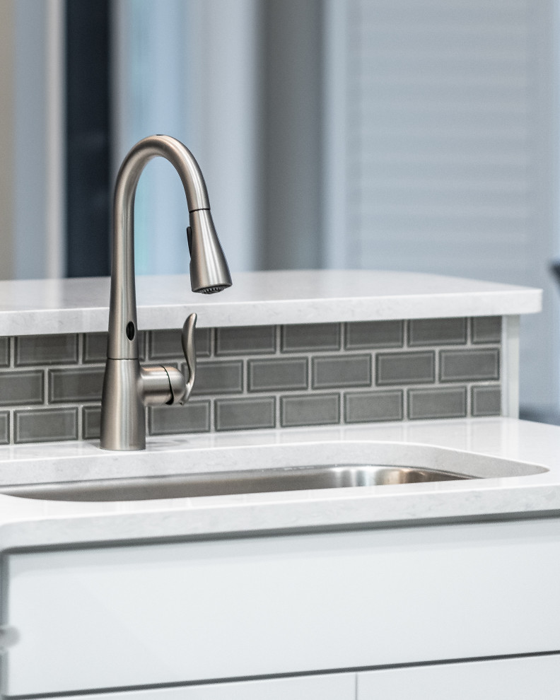 Mid-sized transitional galley porcelain tile and multicolored floor eat-in kitchen photo with an undermount sink, recessed-panel cabinets, white cabinets, quartz countertops, gray backsplash, ceramic backsplash, stainless steel appliances, a peninsula and white countertops