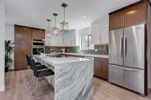 Mid-sized modern l-shaped open plan kitchen in Los Angeles with an undermount sink, flat-panel cabinets, dark wood cabinets, marble benchtops, grey splashback, matchstick tile splashback, stainless steel appliances, with island and light hardwood floors.