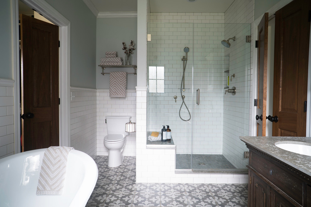 Mid-sized country master bathroom in St Louis with furniture-like cabinets, dark wood cabinets, a claw-foot tub, an open shower, a two-piece toilet, white tile, subway tile, grey walls, porcelain floors, an undermount sink, soapstone benchtops, multi-coloured floor and a hinged shower door.