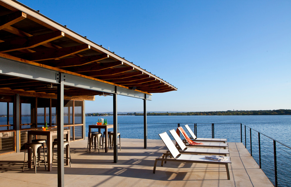 Photo of a contemporary backyard deck in Austin with a roof extension.