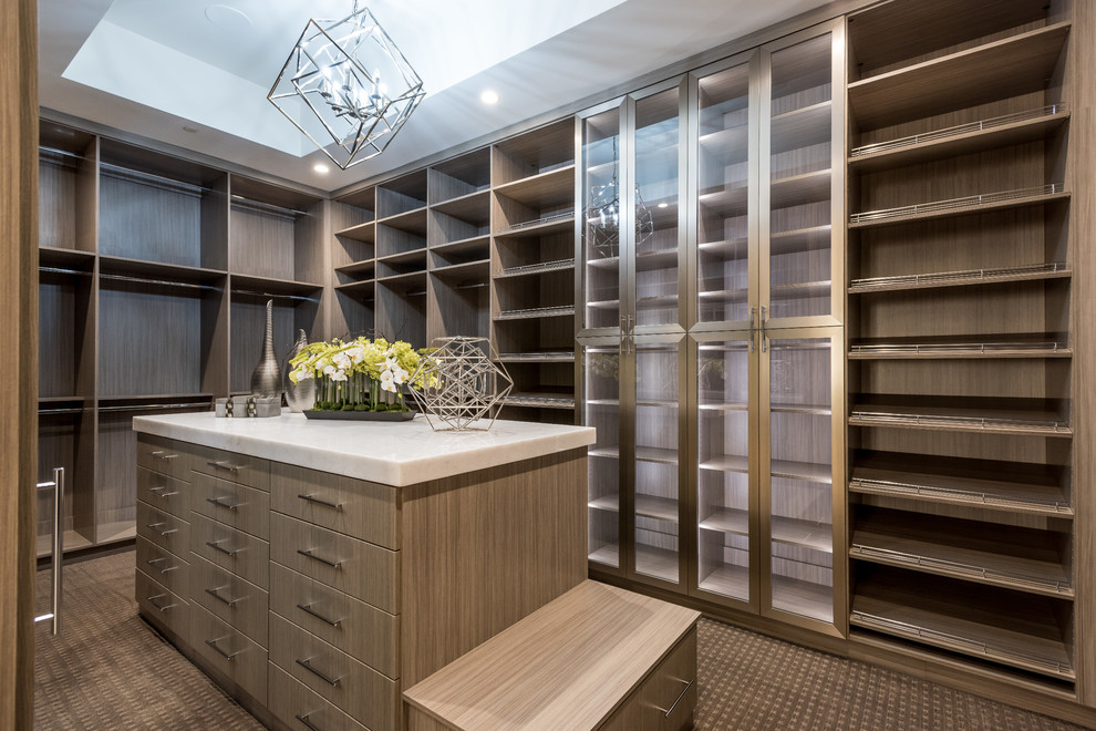 This is an example of a large contemporary gender-neutral dressing room in Las Vegas with flat-panel cabinets, medium wood cabinets, carpet and brown floor.