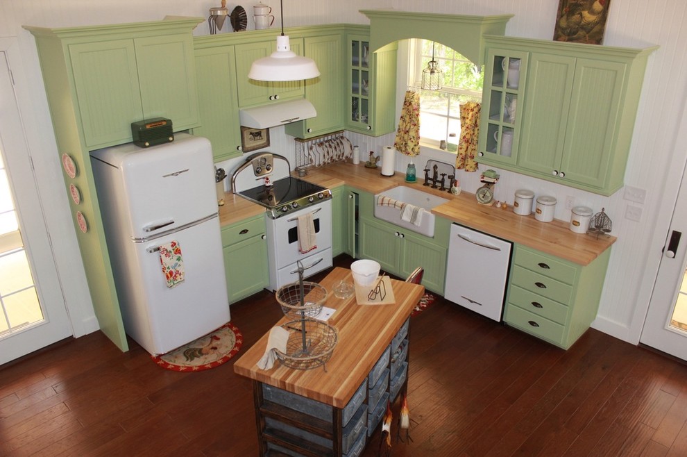 Design ideas for a country l-shaped kitchen in Dallas with a farmhouse sink, recessed-panel cabinets, green cabinets, wood benchtops and white appliances.