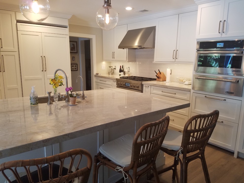 Mid-sized traditional kitchen in Miami with an undermount sink, shaker cabinets, white cabinets, quartzite benchtops, white splashback, subway tile splashback, stainless steel appliances, porcelain floors, with island and brown floor.