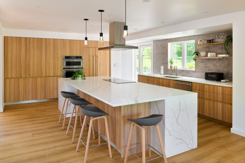 Cette photo montre une cuisine américaine encastrable moderne en L et bois brun avec un évier encastré, un placard à porte plane, un plan de travail en quartz modifié, une crédence grise, une crédence en céramique, îlot et un plan de travail blanc.