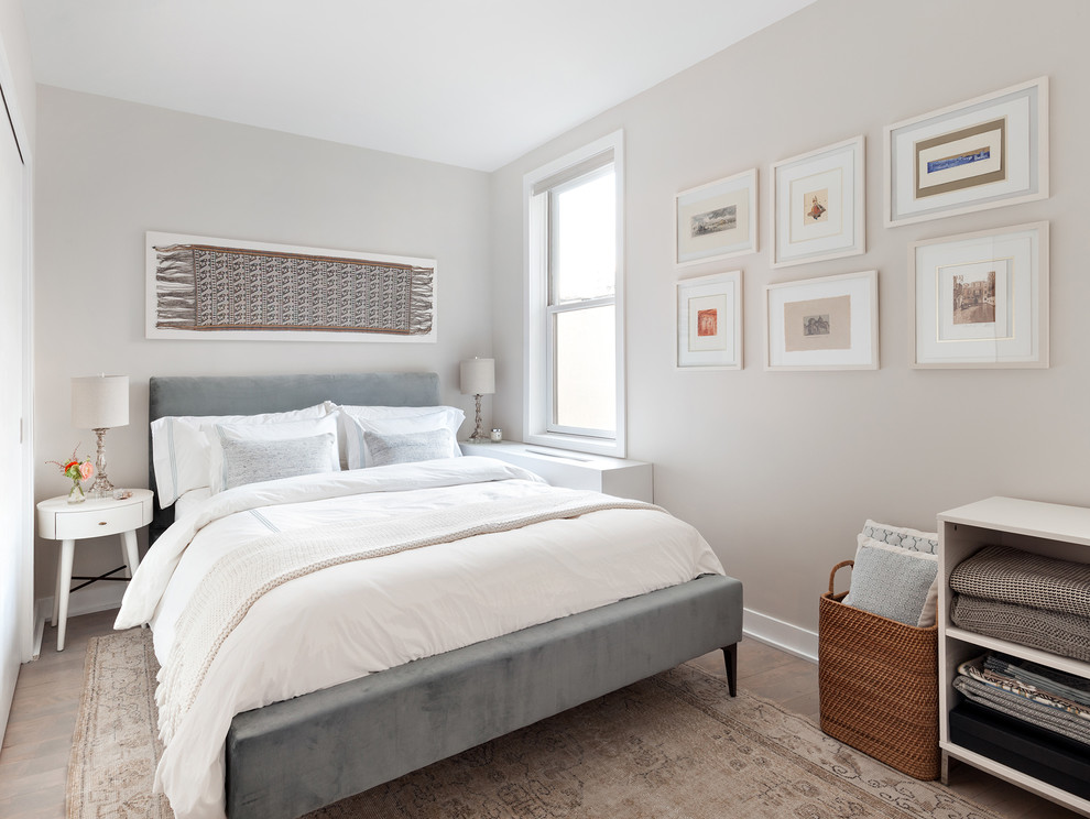 This is an example of a transitional bedroom in New York with beige walls and light hardwood floors.