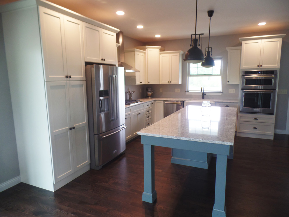 Photo of a mid-sized country l-shaped eat-in kitchen in Cedar Rapids with a farmhouse sink, shaker cabinets, white cabinets, quartzite benchtops, stainless steel appliances, medium hardwood floors and with island.