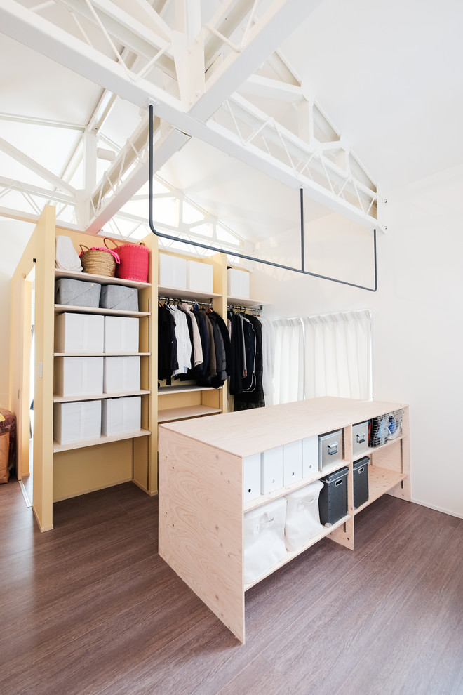 Industrial storage and wardrobe in Tokyo with open cabinets, dark wood cabinets, painted wood floors and brown floor.