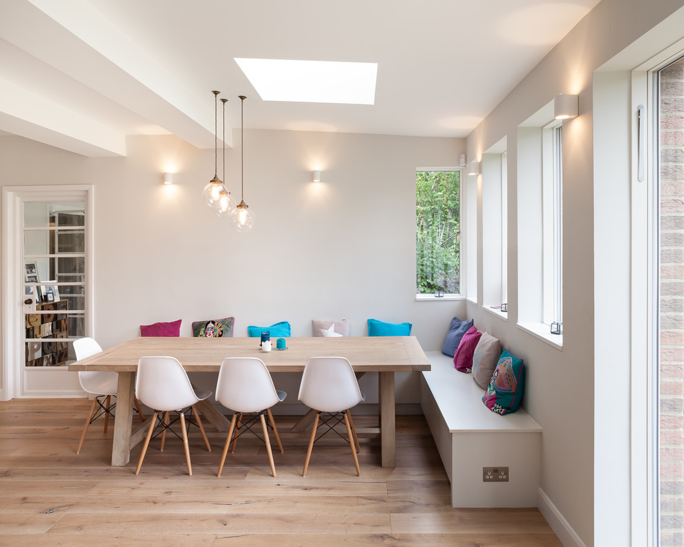 Large contemporary l-shaped kitchen/diner in London with a built-in sink, flat-panel cabinets, grey cabinets, concrete worktops, integrated appliances, medium hardwood flooring and a breakfast bar.