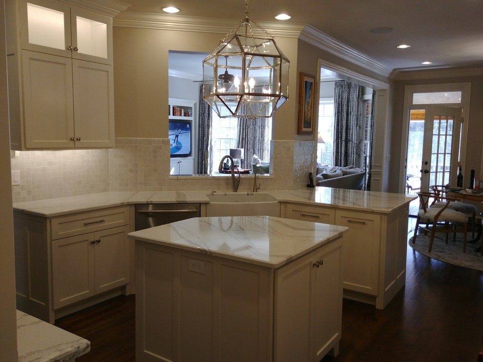 Large transitional single-wall dark wood floor and brown floor enclosed kitchen photo in Nashville with a farmhouse sink, recessed-panel cabinets, white cabinets, quartzite countertops, white backsplash, subway tile backsplash, stainless steel appliances, an island and white countertops