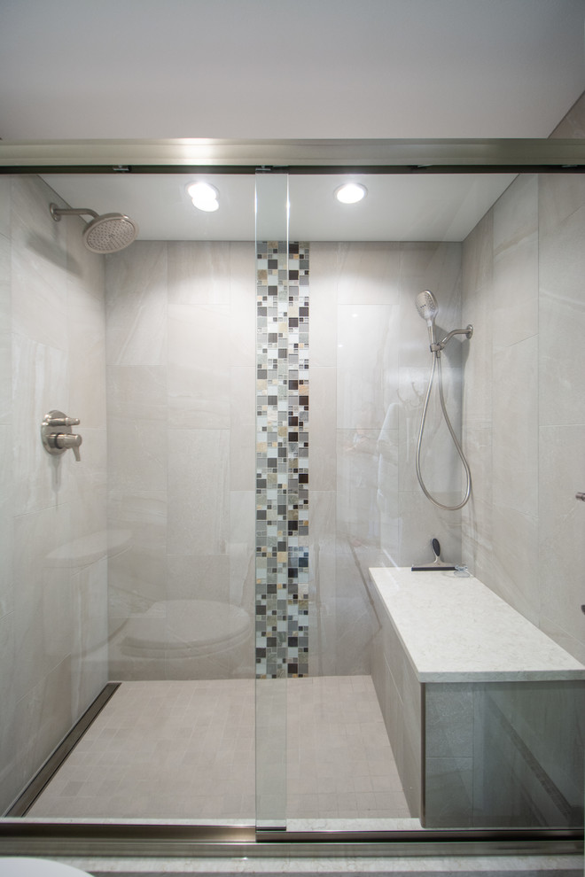 This is an example of a large transitional master bathroom in Denver with shaker cabinets, medium wood cabinets, an alcove shower, a one-piece toilet, gray tile, ceramic tile, grey walls, ceramic floors, an undermount sink, granite benchtops, multi-coloured floor, a sliding shower screen and black benchtops.