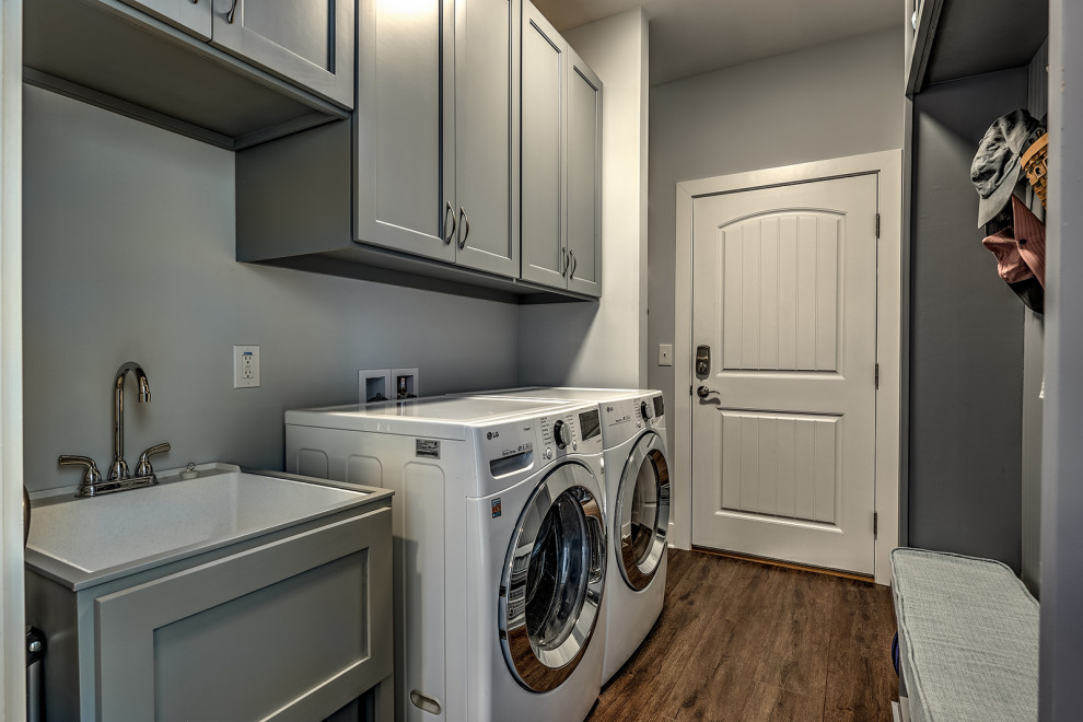 Idéer för att renovera en stor amerikansk parallell tvättstuga enbart för tvätt, med en undermonterad diskho, skåp i shakerstil, grå skåp, beige väggar, vinylgolv, en tvättmaskin och torktumlare bredvid varandra och brunt golv