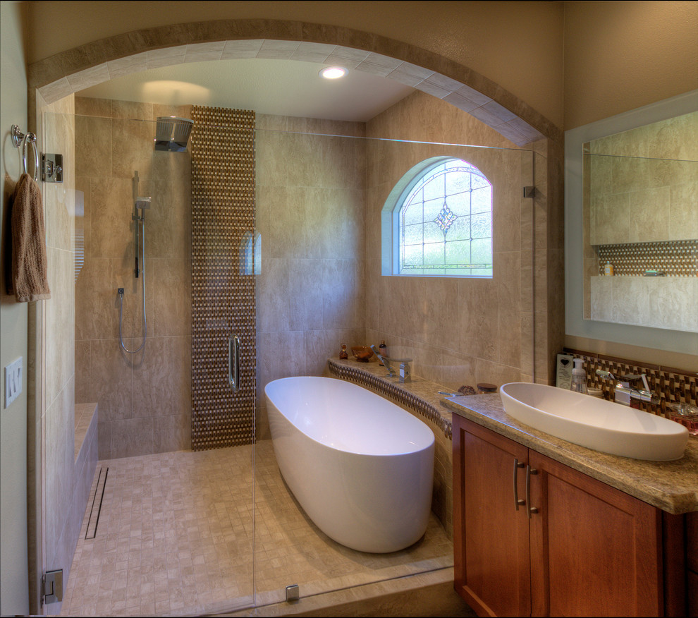 Photo of an expansive contemporary master bathroom in San Diego with raised-panel cabinets, brown cabinets, a japanese tub, a shower/bathtub combo, a two-piece toilet, beige tile, travertine, beige walls, travertine floors, a vessel sink, granite benchtops, beige floor, a hinged shower door and brown benchtops.