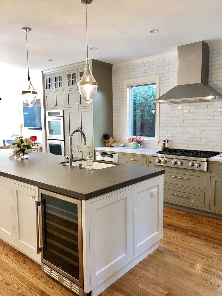 Photo of a mid-sized transitional l-shaped kitchen with an undermount sink, shaker cabinets, beige cabinets, quartz benchtops, white splashback, ceramic splashback, stainless steel appliances, light hardwood floors, with island, brown floor and white benchtop.