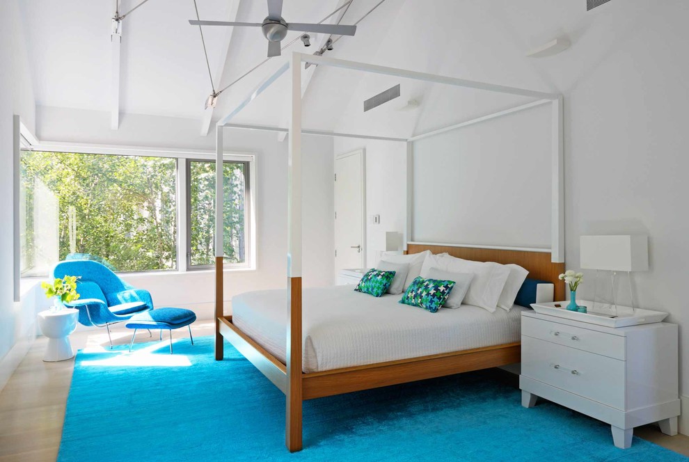 Photo of a contemporary bedroom in New York with white walls and light hardwood floors.
