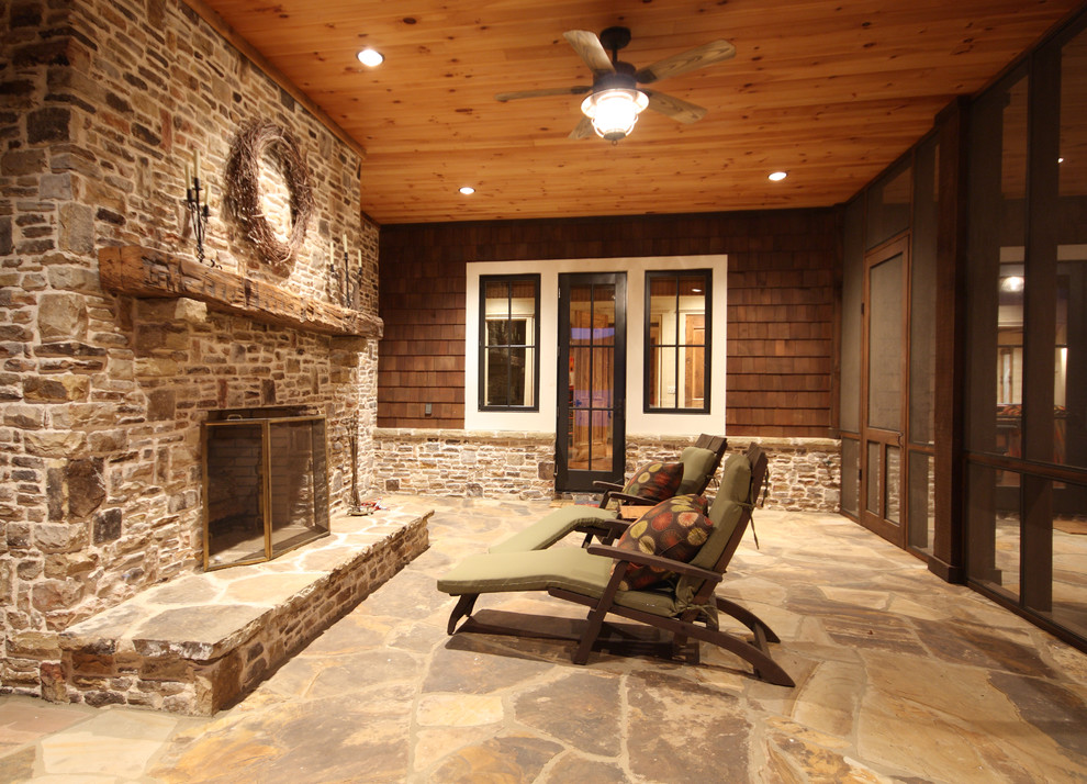 This is an example of a mid-sized country backyard verandah in Atlanta with a fire feature, a roof extension and natural stone pavers.