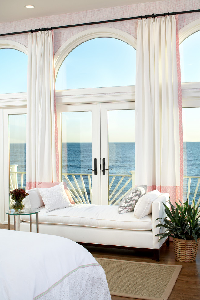 This is an example of a large beach style master bedroom in Boston with medium hardwood floors and pink walls.