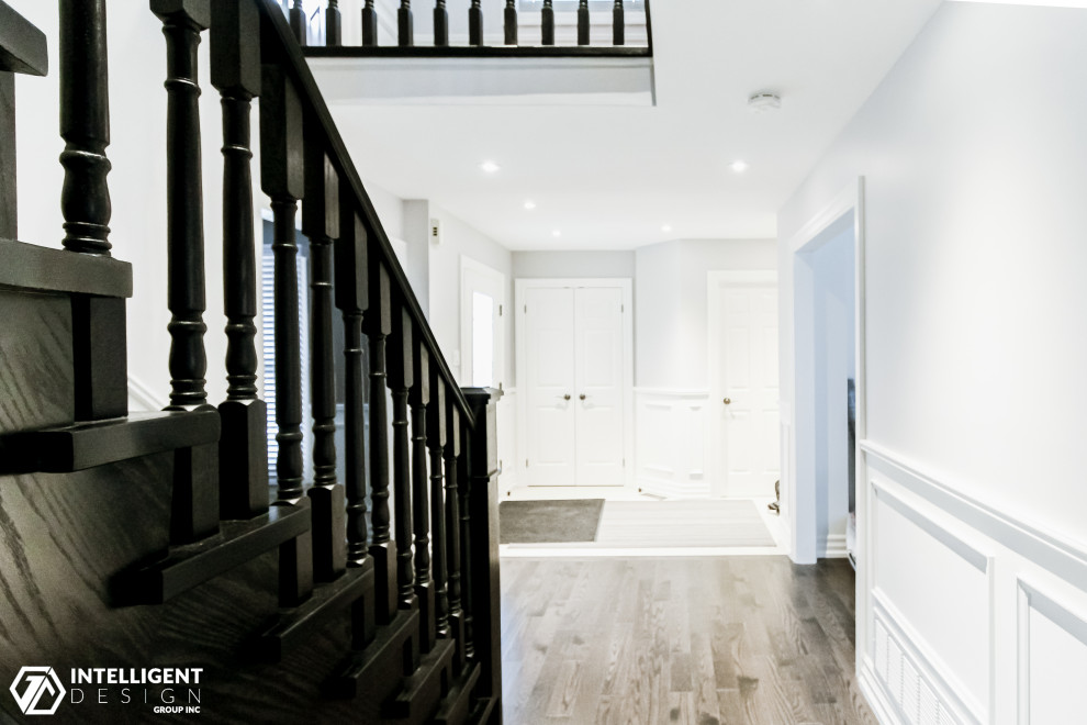 This is an example of a large traditional wood curved staircase in Toronto with wood risers, wood railing and panelled walls.