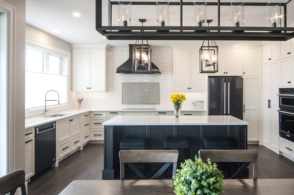 Mid-sized transitional l-shaped eat-in kitchen in Other with an undermount sink, shaker cabinets, white cabinets, marble benchtops, white splashback, subway tile splashback, stainless steel appliances, dark hardwood floors, with island, brown floor and white benchtop.