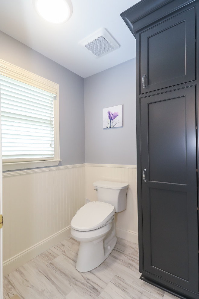 This is an example of a large transitional powder room in Atlanta with beaded inset cabinets, black cabinets, a bidet, white tile, porcelain tile, blue walls, porcelain floors, an undermount sink, engineered quartz benchtops, grey floor, grey benchtops, a built-in vanity and decorative wall panelling.