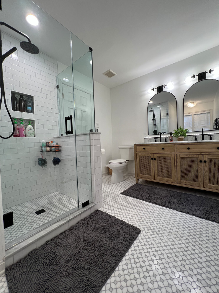 This is an example of a mid-sized transitional master bathroom in Baltimore with furniture-like cabinets, light wood cabinets, a freestanding tub, an alcove shower, a two-piece toilet, white tile, porcelain tile, yellow walls, marble floors, an undermount sink, marble benchtops, grey floor, a hinged shower door, white benchtops, a niche, a double vanity and a freestanding vanity.