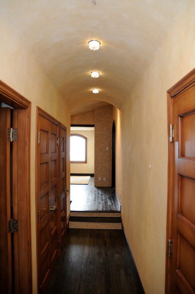 This is an example of a mid-sized traditional hallway in San Diego with yellow walls and dark hardwood floors.