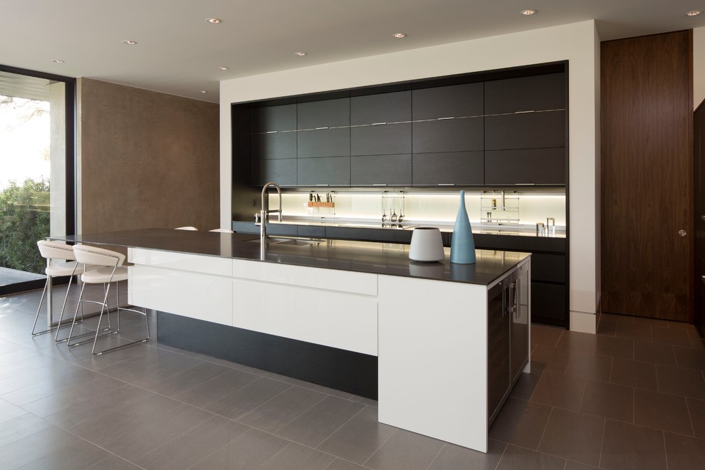 Photo of a large modern galley open plan kitchen in Austin with an undermount sink, flat-panel cabinets, white splashback, glass sheet splashback and porcelain floors.