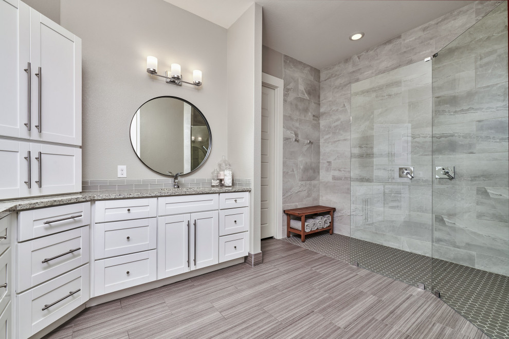 Walk-in shower - transitional gray tile and porcelain tile porcelain tile, brown floor and double-sink walk-in shower idea with shaker cabinets, white cabinets, beige walls, an undermount sink, granite countertops, beige countertops and a built-in vanity