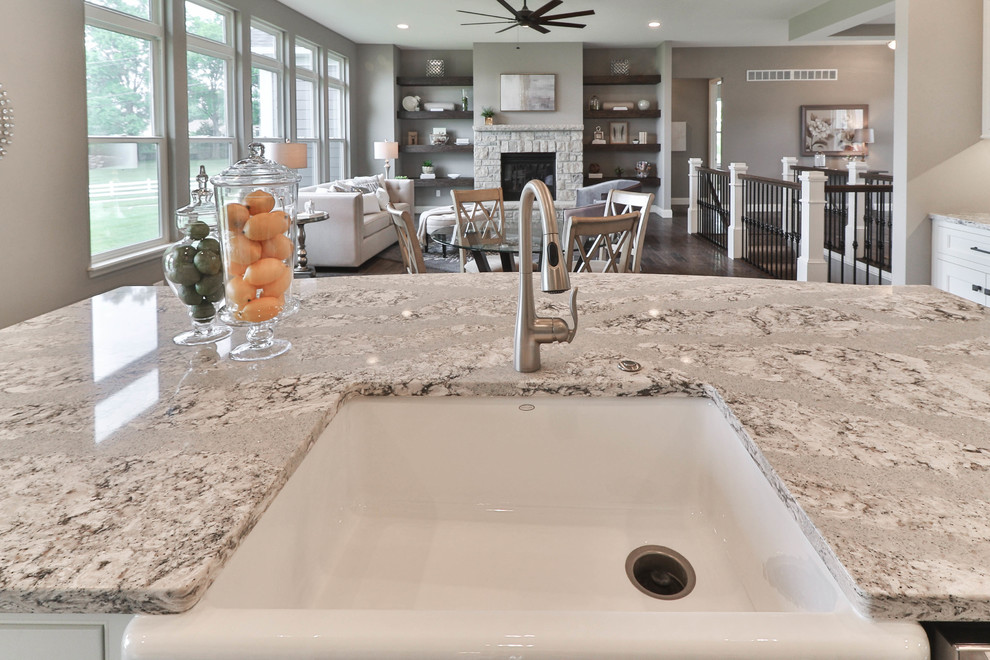 Mid-sized transitional l-shaped dark wood floor and brown floor open concept kitchen photo in St Louis with a farmhouse sink, shaker cabinets, white cabinets, granite countertops, gray backsplash, stainless steel appliances and an island