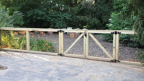 wooden and mesh dog run with a gravel ground cover