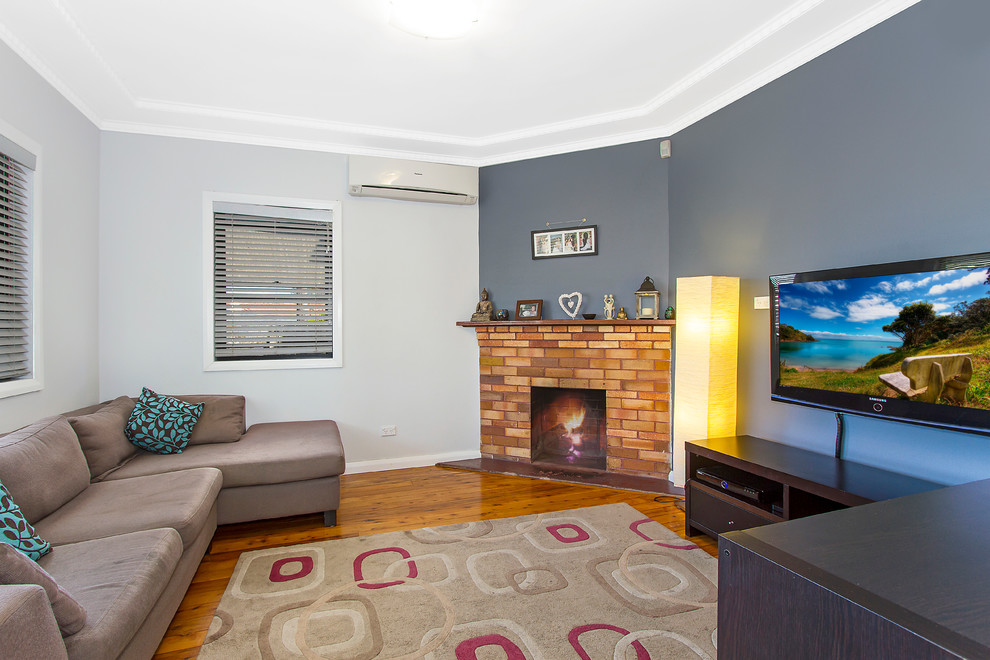 Inspiration for a small modern formal enclosed living room in Sydney with blue walls, dark hardwood floors, a corner fireplace, a brick fireplace surround and a wall-mounted tv.
