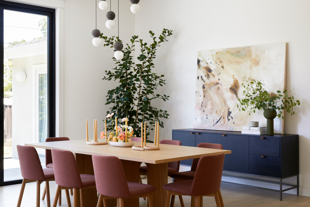 Foto di una sala da pranzo aperta verso il soggiorno scandinava di medie dimensioni con pareti bianche, parquet chiaro, nessun camino e pavimento marrone
