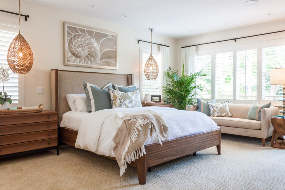 This is an example of a beach style master bedroom in San Diego with beige walls, carpet and beige floor.