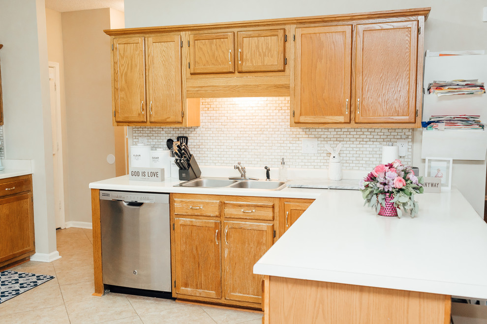 Example of a transitional kitchen design with medium tone wood cabinets, white backsplash, mosaic tile backsplash, stainless steel appliances and white countertops