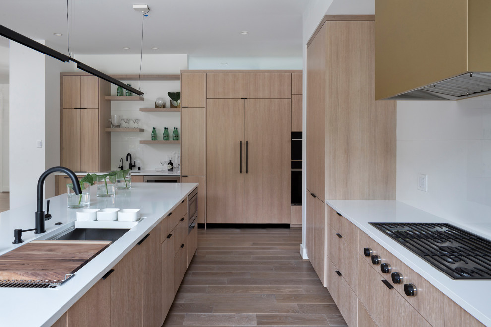 Design ideas for a contemporary kitchen in Minneapolis with a submerged sink, flat-panel cabinets, light wood cabinets, white splashback, integrated appliances, an island and white worktops.