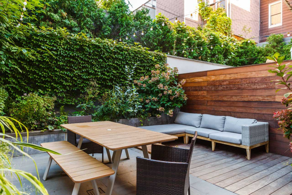 Свежая идея для дизайна: маленький солнечный участок и сад на заднем дворе в современном стиле с перегородкой для приватности, хорошей освещенностью, настилом и с деревянным забором для на участке и в саду - отличное фото интерьера