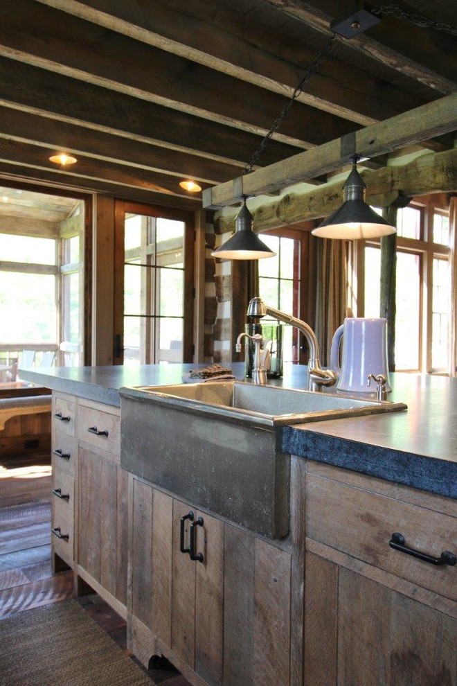 This is an example of a mid-sized country l-shaped open plan kitchen in Other with a farmhouse sink, flat-panel cabinets, distressed cabinets, zinc benchtops, medium hardwood floors and with island.