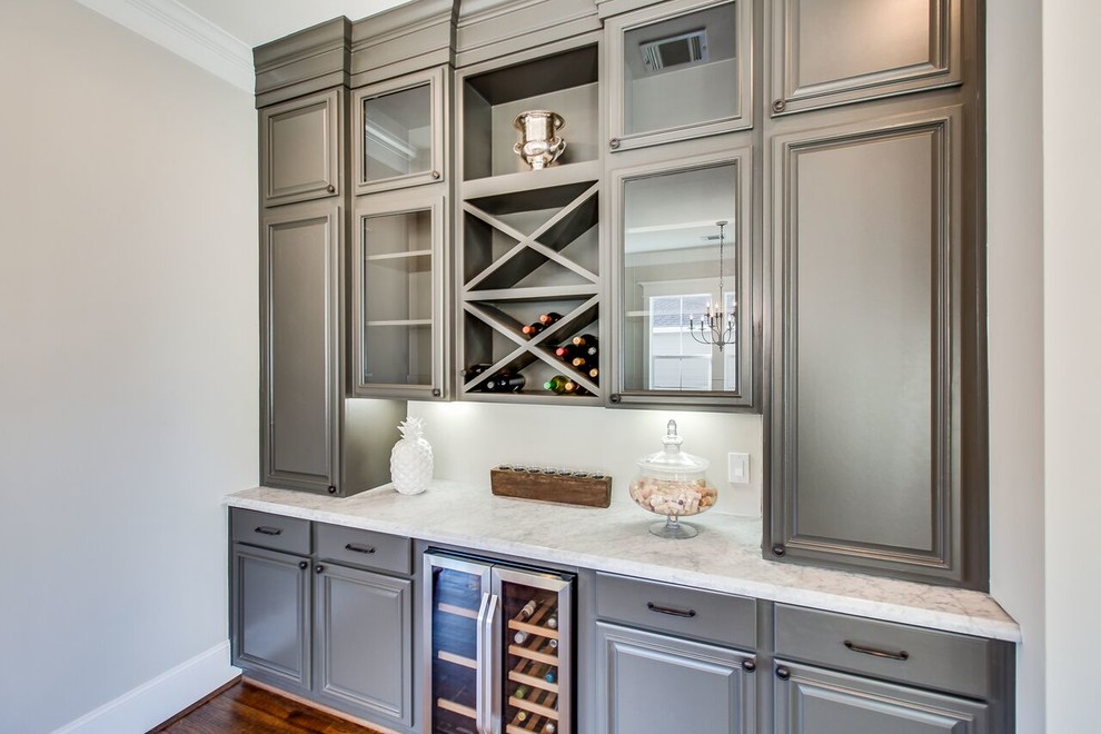 Design ideas for a traditional single-wall home bar in Houston with raised-panel cabinets, grey cabinets, marble benchtops and medium hardwood floors.