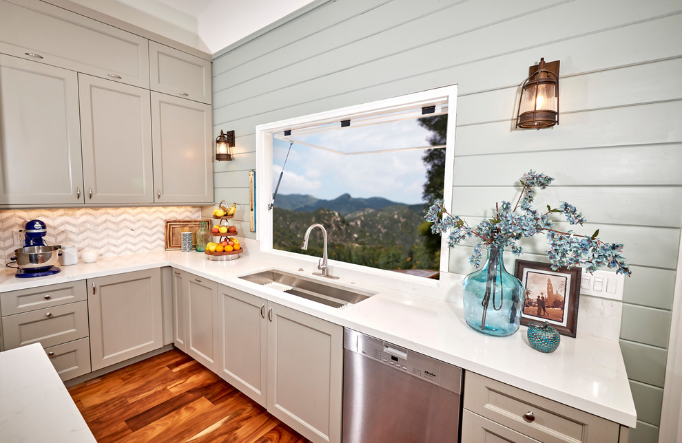 Example of a large transitional l-shaped medium tone wood floor and brown floor open concept kitchen design in Denver with an undermount sink, recessed-panel cabinets, gray cabinets, quartz countertops, white backsplash, marble backsplash, stainless steel appliances, an island and white countertops